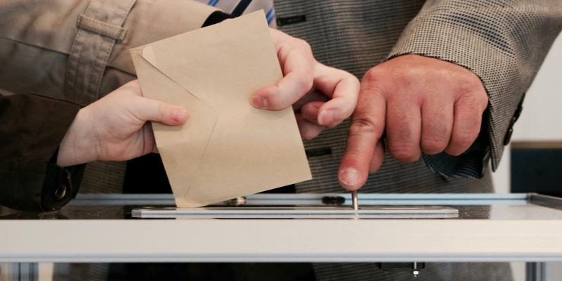 Hands puttiing an envelope in a glass box
