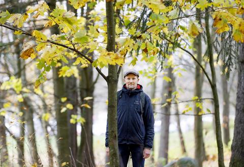 Henkilökuvassa haastateltava Esko Tainio seisoo syksyisessä metsässä puiden keskellä.
